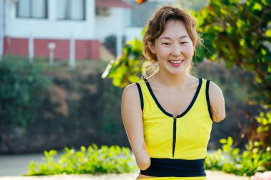 Mutlu Asyalı kolsuz kadın tropik plajda yüzmeden önce ısınıyor.