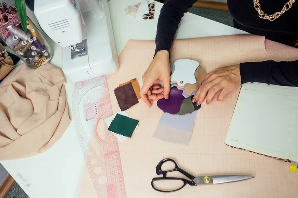 Красивая швея с длинными волосами пишет в блокноте. портной создает коллекцию нарядов. молодая женщина дизайнер одежды, работающая с кожей — стоковое фото
