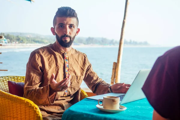 Egyptian man foreign language teacher teaching female student at tropical cafe