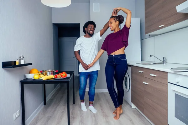 Όμορφη νεαρή Afro αμερικανικό ζευγάρι χαμογελά ενώ χορεύει στην κουζίνα — Φωτογραφία Αρχείου
