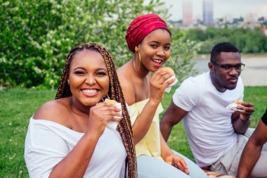 Keyifli Amerika Afrikalı insanlar dışarıda hamburger yiyip eğleniyor. Öğrenciler tatilde. Yaz akşamı hava bulutlu.