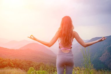 Bir kadın Hindistan 'daki dağların ve çay tarlalarının arka planında yoga yapıyor.