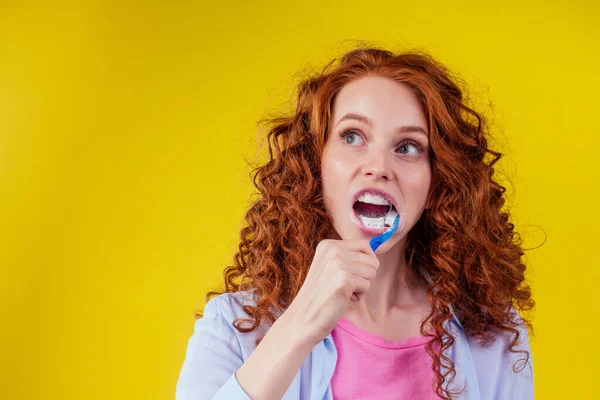 Jengibre pelirrojo mujer somnolienta con cepillo de dientes ecológico y pasta de dientes sobre fondo amarillo estudio — Foto de Stock