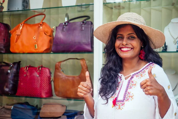 Счастливая индийская женщина в соломенной шляпе и стоять возле витрины с модными сумками в Индии Гоа рынок — стоковое фото