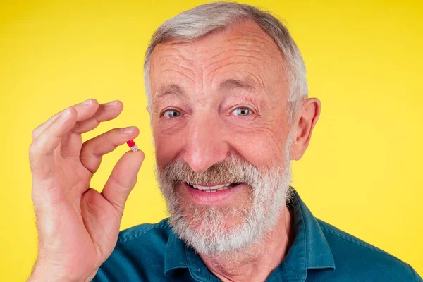 Heureux vieil homme tenant des vitamines studio fond jaune — Photo