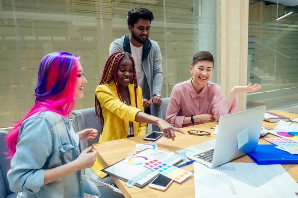 Yaratıcı ajans tasarım ekibi birlikte çalışıyor. Rasta örgülü Afro-Amerikan kadın ve Kafkasyalı kız. Ofisteki Hintli adamla pembe mavi saç teli.