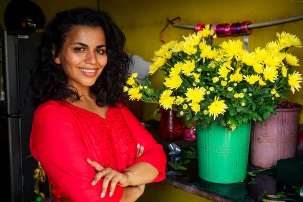 Fröhliche junge Frau brünette Floristin verkauft Blumen in einem Blumenladen — Stockfoto