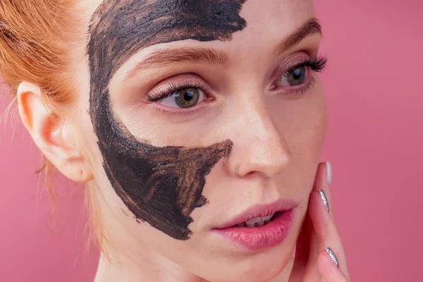 Κοκκινομάλλα τζίντζερ νεαρή καυκάσια γυναίκα με φυσική μάσκα κατά της ακμής στο όμορφο τέλειο πρόσωπό της σε στούντιο ροζ φόντο — Φωτογραφία Αρχείου
