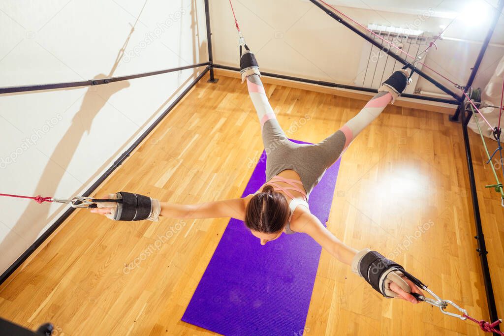 Sporty young caucasian woman doing stretching exercises of full body muscles workout on stretch aerobic aero strap in gym,yogi mat