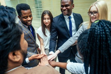 Uluslararası iş ortaklarından oluşan takım çalışması: Hintli, Koreli, Afro-Amerikalı insanlar modern odada birlikte çalışıyorlar.