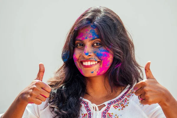 Festival Holi de Colores. Retrato de chica india feliz en holi color.she mostrando el gesto pulgares hacia arriba —  Fotos de Stock