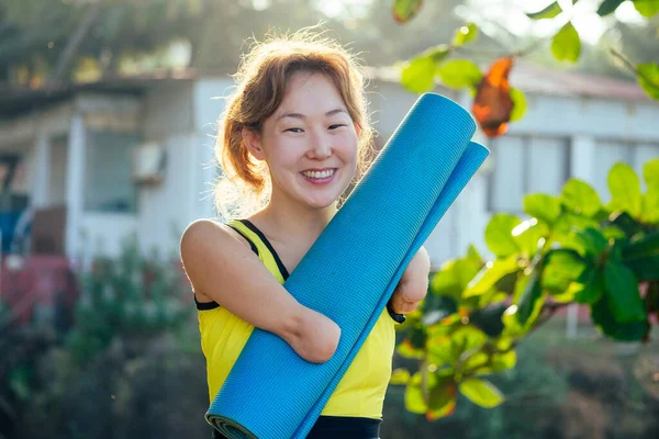 Mutlu Asyalı kolsuz kadın tropik plajda yüzmeden önce ısınıyor.