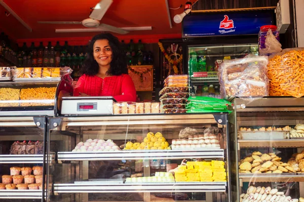 Mutlu Hindistanlı kadın Goa 'da yerel bir şekerci dükkanında şekerleme satıyor.