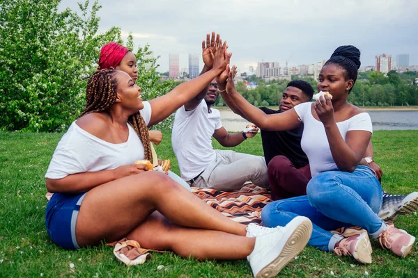 Happy casual america african people having fun and eating burger outdoors lifestyle,students for a break summer evening cloudy weather in park — Stock Photo, Image