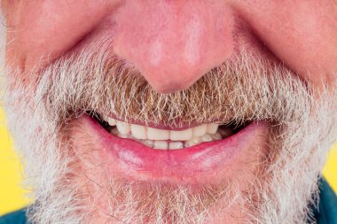 Yakışıklı, mutlu, olumlu ve tatmin edici, iyi kar beyazı dişler. Sahte diş stüdyoları sarı arka plan.