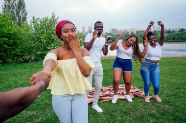 Güzel, gülümseyen afro örgü ören sarıklar ve büyük yuvarlak küpeler erkek arkadaşını arkadaşlarıyla dans etmeye götürüyor.