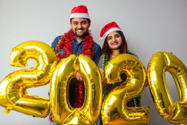 Mutlu adam güzel kadın ve hava balonları tutuyor 2020 yılbaşı günü Hindistan 'da, oturma odasında.