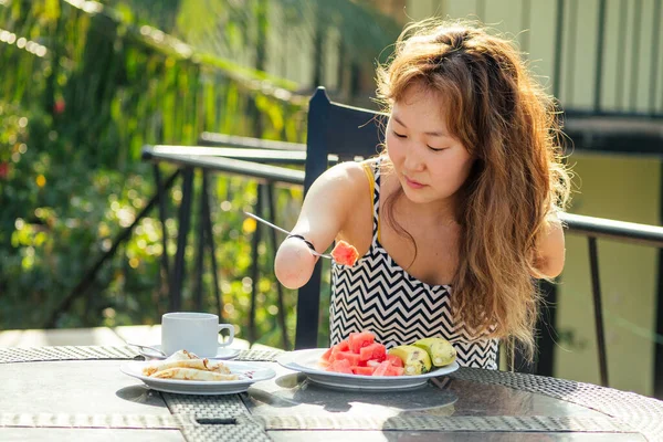 Beautiful asian woman eating breakfast at tropical resort.she is drinks cup of tea or coffee — Stock Photo, Image