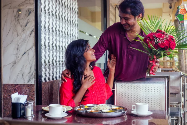 Красивый мужчина закрывает глаза на свою девушку, чтобы сделать романтический сюрприз в ресторане летом тропического кафе городского пляжа День Святого Валентина — стоковое фото