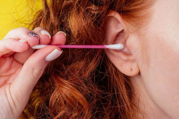 Rizado pelirroja caucásica mujer uso orejas palos en estudio amarillo fondo — Foto de Stock