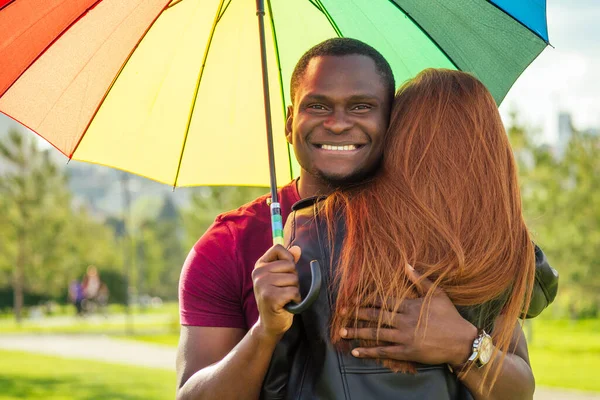 赤髪の生姜女とアフリカ系アメリカ人の男が夏の公園の傘の下で — ストック写真