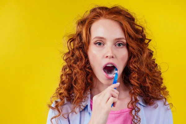 Jengibre pelirrojo de mujer con cepillo de dientes ecológico y pasta de dientes sobre fondo amarillo estudio — Foto de Stock