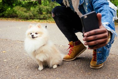 Afrikalı Amerikalı adam yaz parkında pofuduk Spitz ile kendi portresini yapıyor.