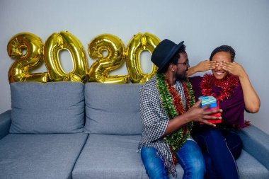 Birbirine aşık çok uluslu bir çift Noel arifesinde oturma odasında kanepede oturmuş hediyelerini değiş tokuş ediyorlar.