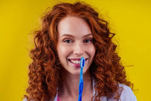 Jengibre pelirrojo de mujer con cepillo de dientes ecológico y pasta de dientes sobre fondo amarillo estudio — Foto de Stock