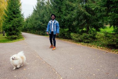 Afro-Amerikan adam pofuduk tükürüğüyle sokakta yürüyor, eğitimli köpek takımları eğitiyor.