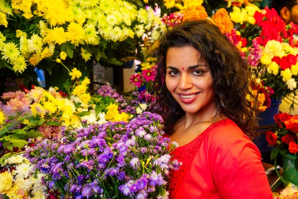 Портрет брюнетки индийской флористки на цветочном базаре, смотрящей в камеру и улыбающейся — стоковое фото