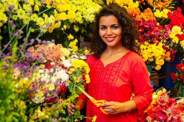 Porträt einer brünetten indischen Floristin in einem Blumenbasar, die in die Kamera blickt und lächelt — Stockfoto