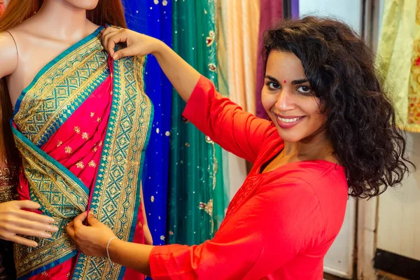 Bruna donna indiana che sceglie un nuovo saree tradizione in market.needlewoman designer drappeggio abito in tessuto su un manichino — Foto Stock