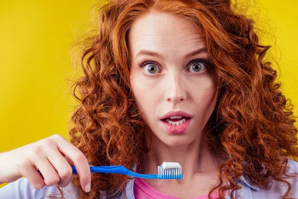 Pelirroja jengibre mujer cepillarse los dientes con pasta de dientes eco pasta en amarillo fondo del estudio — Foto de Stock