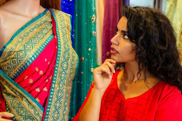 Bruna donna indiana che sceglie un nuovo saree tradizione in market.needlewoman designer drappeggio abito in tessuto su un manichino — Foto Stock