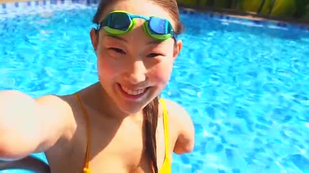 Beautiful young armless woman training to swim in pool at tropical resort taking selfie on smartphone camera — Stock Video
