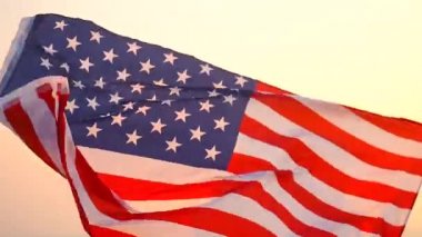 Güneşin doğuşunda Amerikan bayrağıyla denizde güzel genç bir kadın.