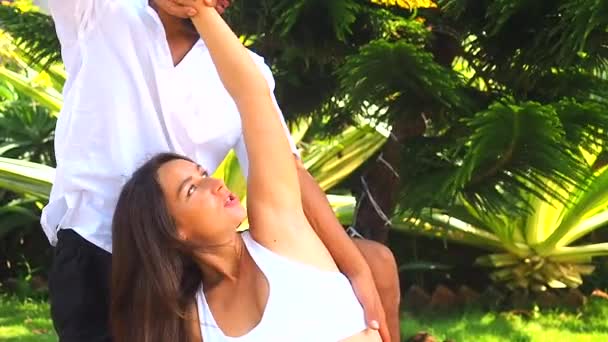 Щаслива дружина вагітності і азіатський чоловік робить пару медитацій в зеленому парку на морському пляжі — стокове відео