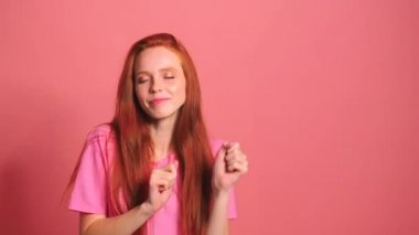 Pembe stüdyo arka planındaki kızıl saçlı kadın gülümse ve kendini iyi hisset.