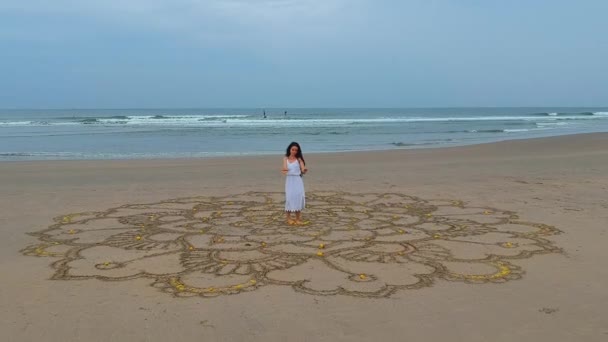 Woman drawing the big mandala at sand and dancing in empty beach top view above from drone quadrocopter.concept of femininity and independence — Stock Video