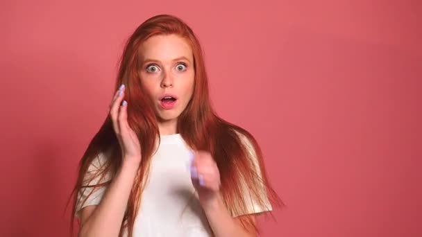 Scared shocked redhaired ginger woman in pink studio background — Stock Video