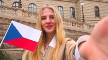 Prag 'ın eski meydanında elinde çekiç bayrağı olan genç bir kadın turist. Çek Cumhuriyeti 'nde harika bir tatil ve kameralı telefondan selfie çekmek.