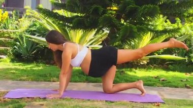Hamile sağlıklı kadın deniz kıyısındaki tropikal parkta meditasyon yapıyor.
