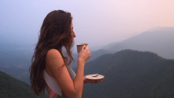 Güzel kız Hindistan tepelerindeki organik taze kahvenin ya da masala çayının tadını çıkar. Akşam günbatımında manzarası çok güzel. — Stok video