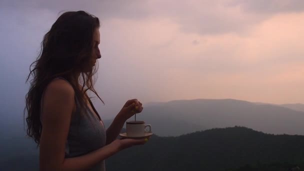 Krásná dívka vychutnat organické čerstvé kávy nebo masala chai v indických kopcích s horním krásným výhledem na západ slunce — Stock video