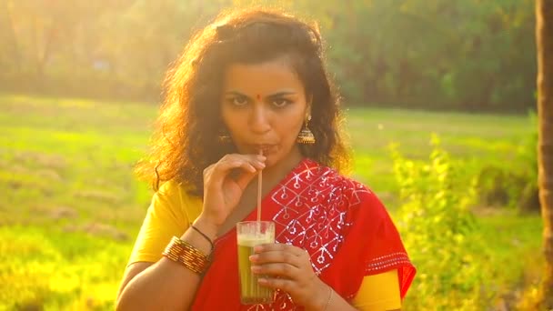 Piękno indyjski portret kobieta pije słodkie świeże sok wiejskie rośliny przyprawy i plantacji ryżu tło — Wideo stockowe