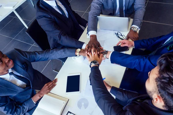 boss afro businessmen talking with arab and india partners colleague, multiethnic team sitting at a table with a laptop and documents in the office with panorama window.contract signature idea