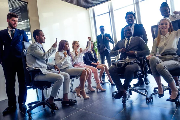 Mujer de negocios de raza mixta y hombre de negocios planteado juego en sillas de montar en la ventana panorámica moderna oficina —  Fotos de Stock