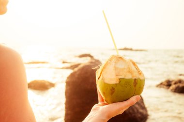 Elinde plastik tüp olan hindistan cevizi. Plajdaki kadın.