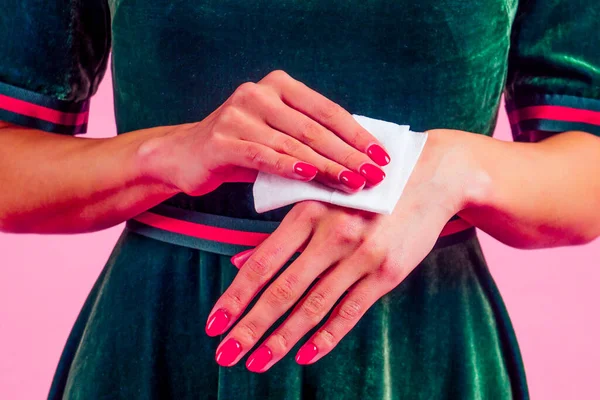 Дівчина використовує мокрі серветки піт-рука, застосовуючи дезінфікуючий засіб для рук на рожевому фоні в студії — стокове фото